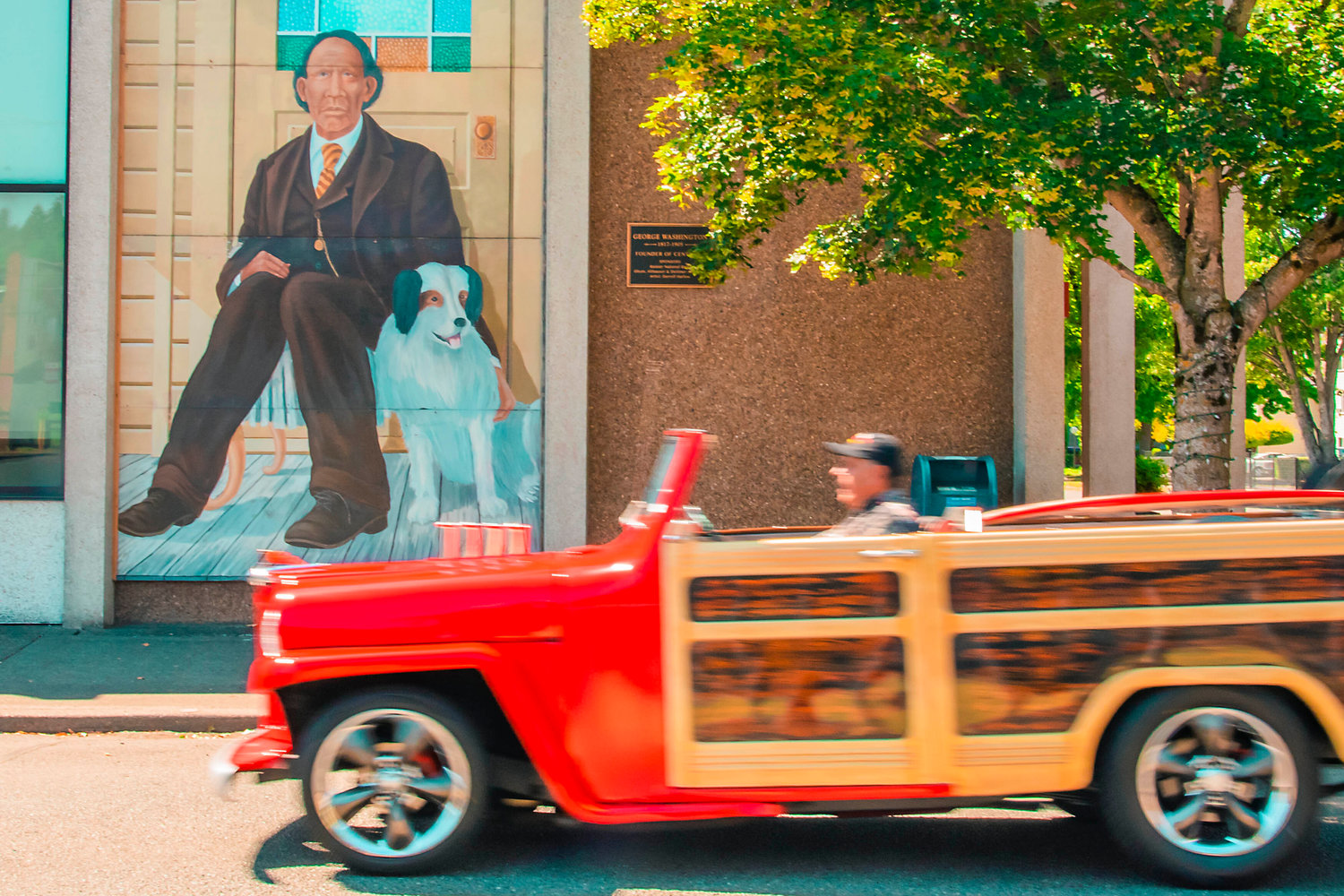 Vintage vehichles drive by a mural of George Washington in downtown Centralia following Summerfest activities for Fourth of July, Sunday afternoon.